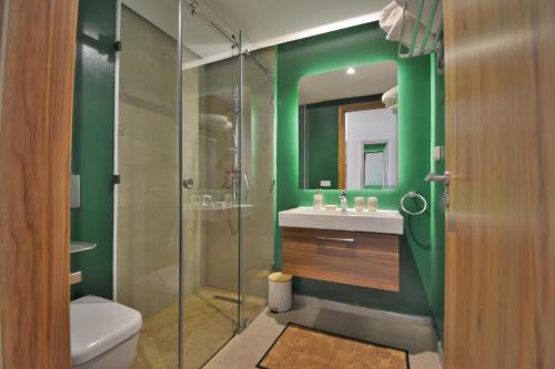 a bathroom with green walls and a glass shower at Appartement Domaine de Noria in Marrakech