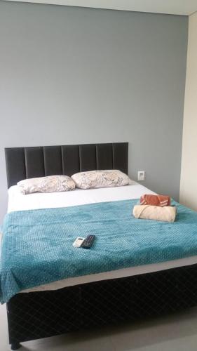a bed with a blue blanket and two pillows on it at Pousada Maranata Canoas in Canoas