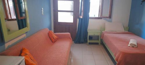 a room with two beds and a couch and a window at Selena Rooms in Agia Galini