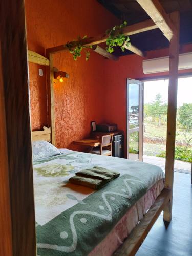 a bedroom with a bed and a desk and a window at Vila Ecológica Cambará in Cambará