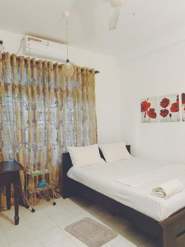 a bedroom with a bed and a curtain and a table at Unawatuna House in Unawatuna
