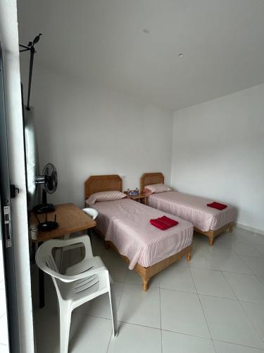 a room with two beds and a table and a chair at Espace socio culturel Dr Masmudi in Belyounech 