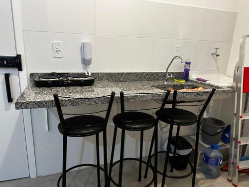 a kitchen with four bar stools at a counter at Studio BQ 3 in Barbacena