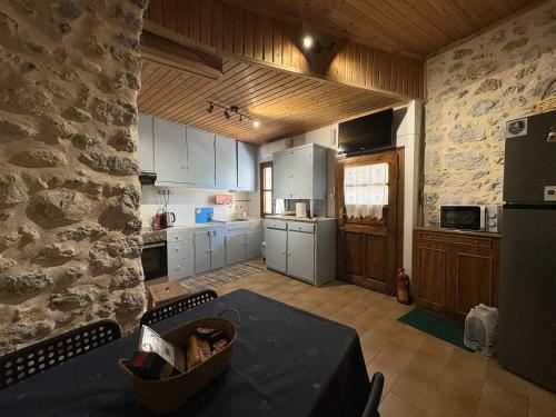 a kitchen with white cabinets and a stone wall at Το σπίτι του Καντήλα in Leonidion