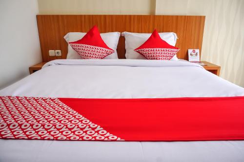 a red and white bed with red pillows on it at Hotel O Bukittinggi near Jam Gadang formerly Hotel Aedo in Bukittinggi
