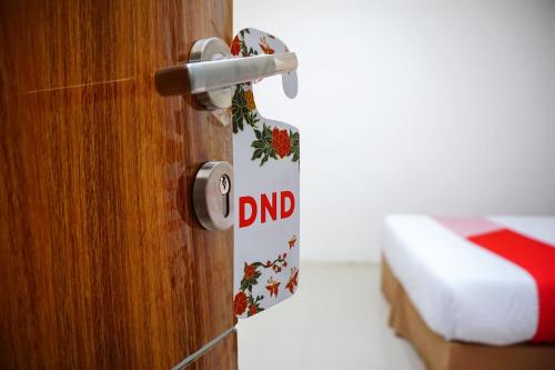 a door with a dnd sign on it next to a bed at Hotel O Bukittinggi near Jam Gadang formerly Hotel Aedo in Bukittinggi