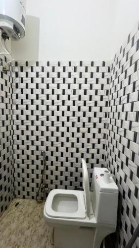 a bathroom with a white toilet and black and white tiles at Lotus of Creation in Pushkar