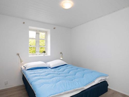 a large blue bed in a white room with a window at 16 person holiday home in Nykøbing M in Jørsby