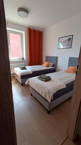 a bedroom with three beds and a red curtain at Cozy Duo in Zduńska Wola