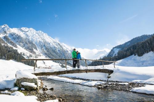 two people standing on a bridge over a river in the snow at Apart Garber in Zellbergeben