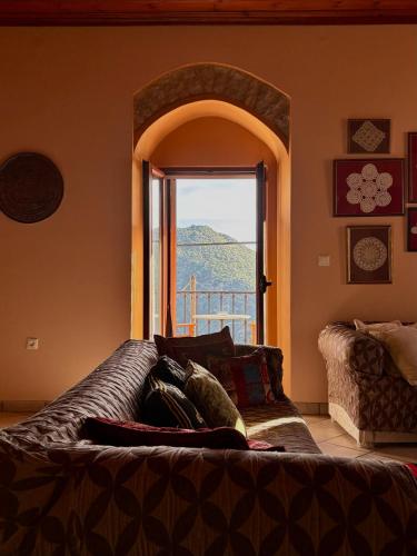 a living room with a couch and a large window at Sophia's Stone House in Dhimitsana