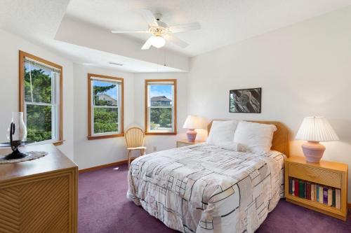 a bedroom with a bed and a desk and windows at 8455 - Mad Hatteras in Avon