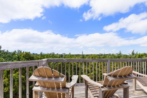 two wooden chairs sitting on a deck with a view at 8455 - Mad Hatteras in Avon