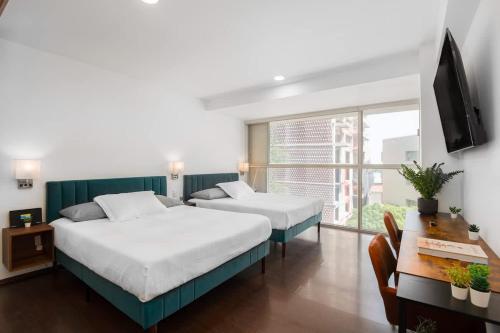 a bedroom with two beds and a desk and a television at Hidden Gem Collection Interlomas in Mexico City