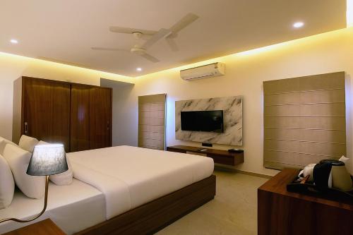 a bedroom with a bed and a flat screen tv at PINNACLE Udaipur - Boutique Rooftop Pool Hotel, Near the Lakes in Udaipur