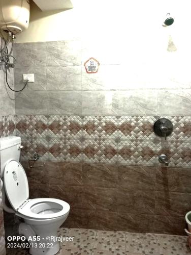 a bathroom with a toilet and a tiled wall at ARITHANG TASHI near M G marg in Gangtok