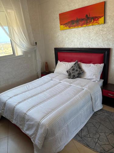 a bedroom with a large white bed with a red headboard at Jnane dalia in Bouznika