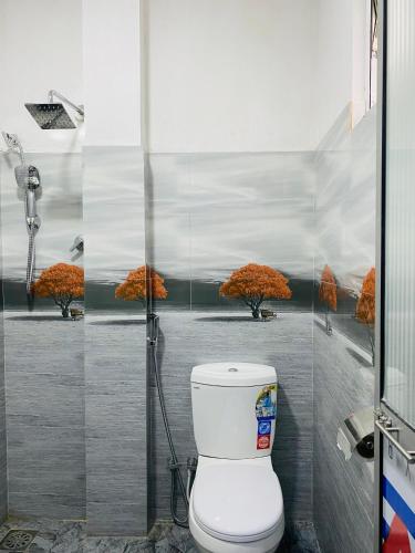 a bathroom with a toilet with a painting of trees at Ella Hidden Ferns in Ella