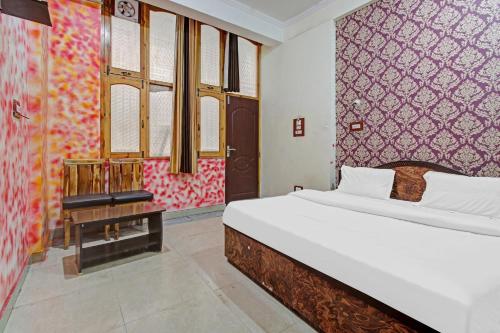 a bedroom with a white bed and a red wall at Hotel O Shaani Guest House in Jawāharnagar