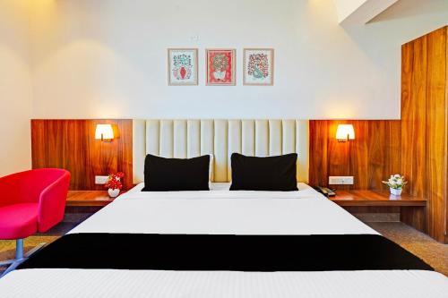 ニューデリーにあるHotel IVYのベッドと赤い椅子があるホテルの部屋