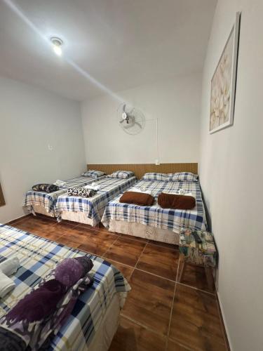 three beds in a room with wooden floors at FAMÍLIA CHARLEAUX in Aparecida