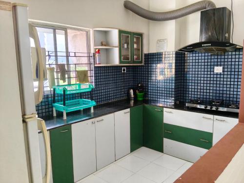 a kitchen with green and white cabinets and blue tiles at Mimo's in Guwahati