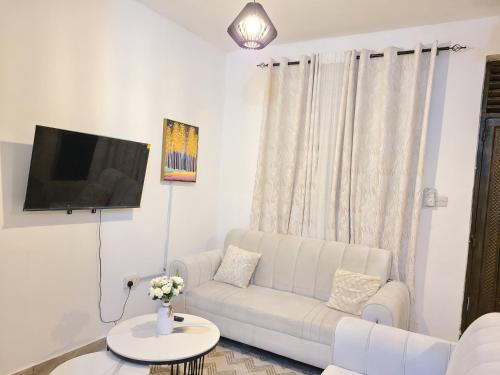a living room with a white couch and a tv at Stayswithyezzy in Mtwapa