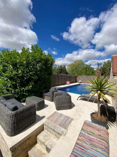 a swimming pool with wicker chairs and a palm tree at Gîte "La petite pompe" avec piscine et spa in Prissac