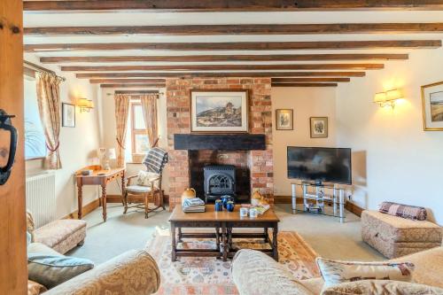 a living room with a couch and a fireplace at Maple Cottage - Rural Charm & Cotswold Views in Dumbleton