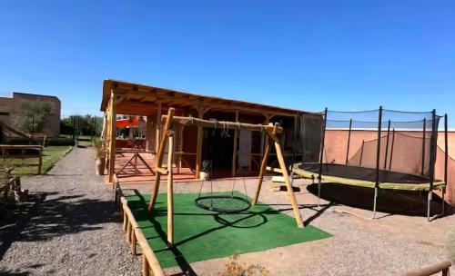 a playground with a swing set in front of a building at Villa Dar Hamza Marrakech in Tahannout