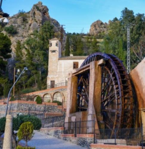a building with a wheel in front of a mountain at Atico de lujo con jacuzzi, piscina y gimnasio cerca de Balneario de Archena in Villanueva de Río Segura