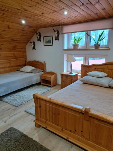 zwei Betten in einem Zimmer mit Holzwänden in der Unterkunft Ciurkówka in Sieniawa