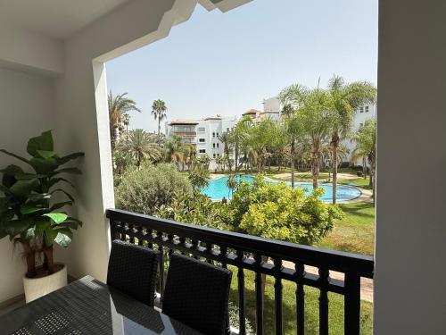 a balcony with a view of a pool and palm trees at AGADIR MARiNA - LUXURY BEACHFRONT APARTMENT in Agadir