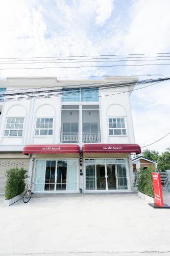 a white building with windows and a bike parked in front at no 185 hostel in Ban Pak Nam Pran