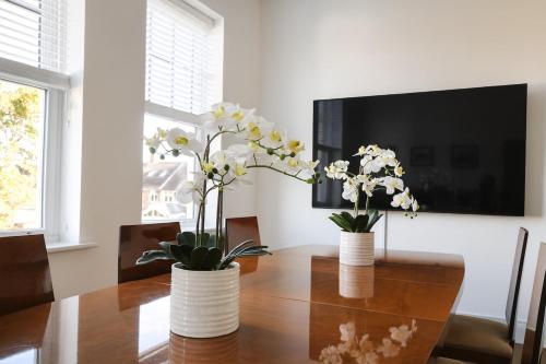 zwei Vasen mit weißen Blumen auf einem Holztisch in der Unterkunft Northampton 3 Bed 3 Bathroom New Duplex Apartment in Spinney Hill