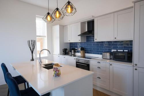 eine Küche mit weißen Schränken und einer weißen Arbeitsplatte in der Unterkunft Northampton 3 Bed 3 Bathroom New Duplex Apartment in Spinney Hill