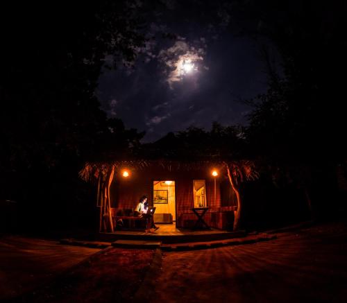 a man sitting at a table in front of a house at night at Safaria Lodge Wilpattu in Pahala Maragahawewa