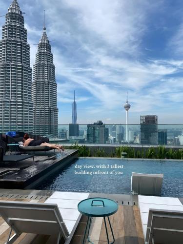 a woman laying on the edge of a swimming pool with a city skyline at Premier Suites Twin Towers at Star Residences in Kuala Lumpur