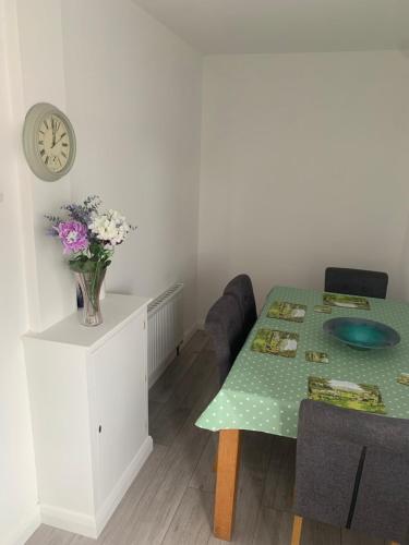 a dining room with a table and a clock on the wall at 169 Benbradagh View in Dungiven
