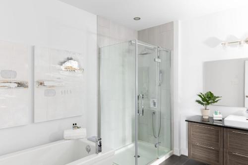 a white bathroom with a shower and a sink at Modern 2BR Loft Condo with Rooftop Patio and Parking in Gatineau