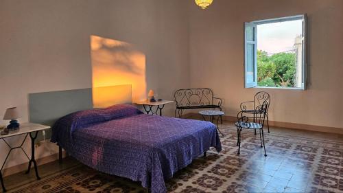 a bedroom with a bed and two chairs and a window at Villa Mozia riserva dello Stagnone in Marsala