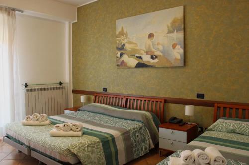 a bedroom with two beds and a painting on the wall at Hotel L'AQUILA 99 in LʼAquila