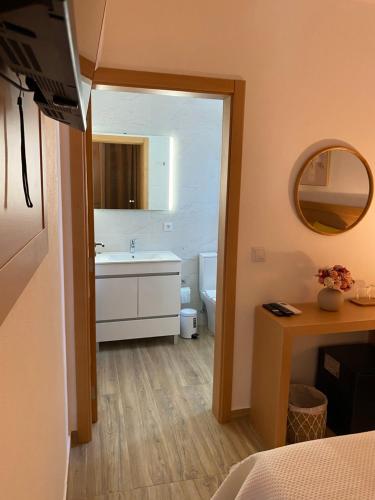 a bathroom with a sink and a toilet and a mirror at Vivenda Por do Sol in Couço