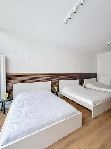 Habitación con 2 camas, paredes blancas y suelo de madera. en Central Spot - Louise, en Bruselas