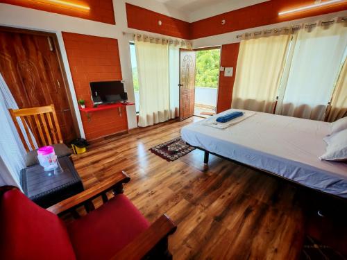 a bedroom with a bed and two chairs and a television at Abaca AuroVibe in Kuilapayam