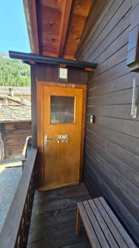 a wooden door in the side of a building with a bench at Lonys Wanderlust Nahe Zermatt in Sankt Niklaus