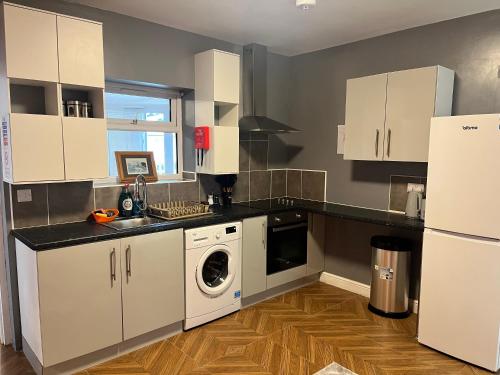 a kitchen with white cabinets and a washer and dryer at Bacton Coastal Retreat in Bacton