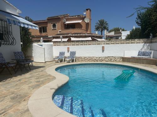 a swimming pool with chairs in front of a house at La Duna de Denia in Denia