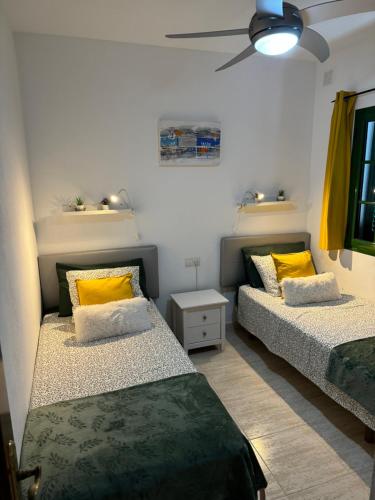 2 Betten in einem Zimmer mit gelben Kissen in der Unterkunft Villa Karisa in Playa Blanca