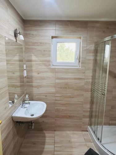 a bathroom with a sink and a shower at Tenisz vendégház in Ordacsehi